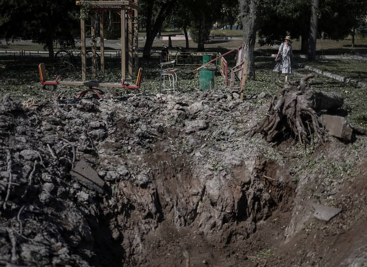 Местный житель идет возле воронки на детской площадке в городе Дружковка